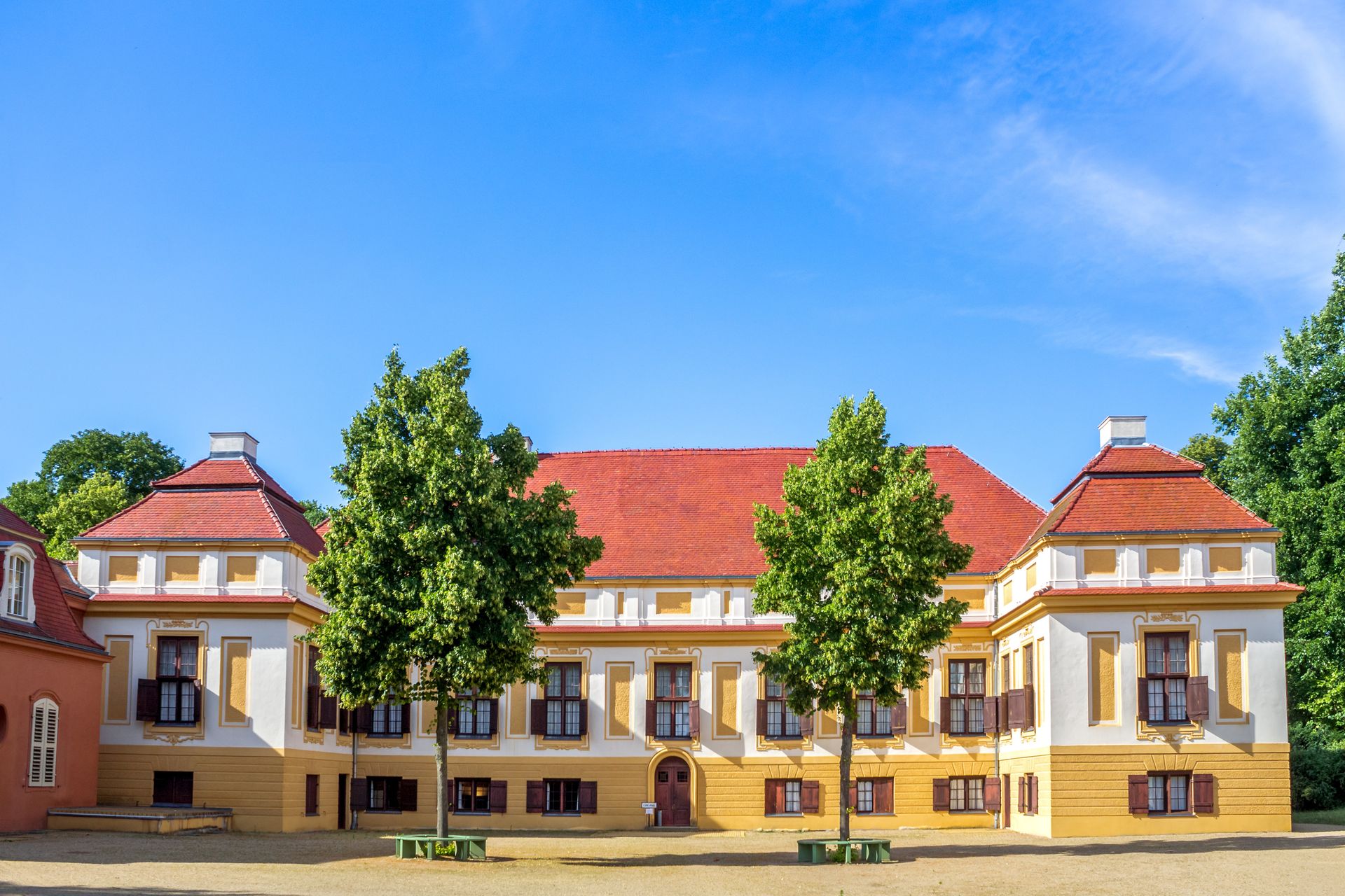 Ein großes Gebäude mit einem roten Dach und Bäumen davor.