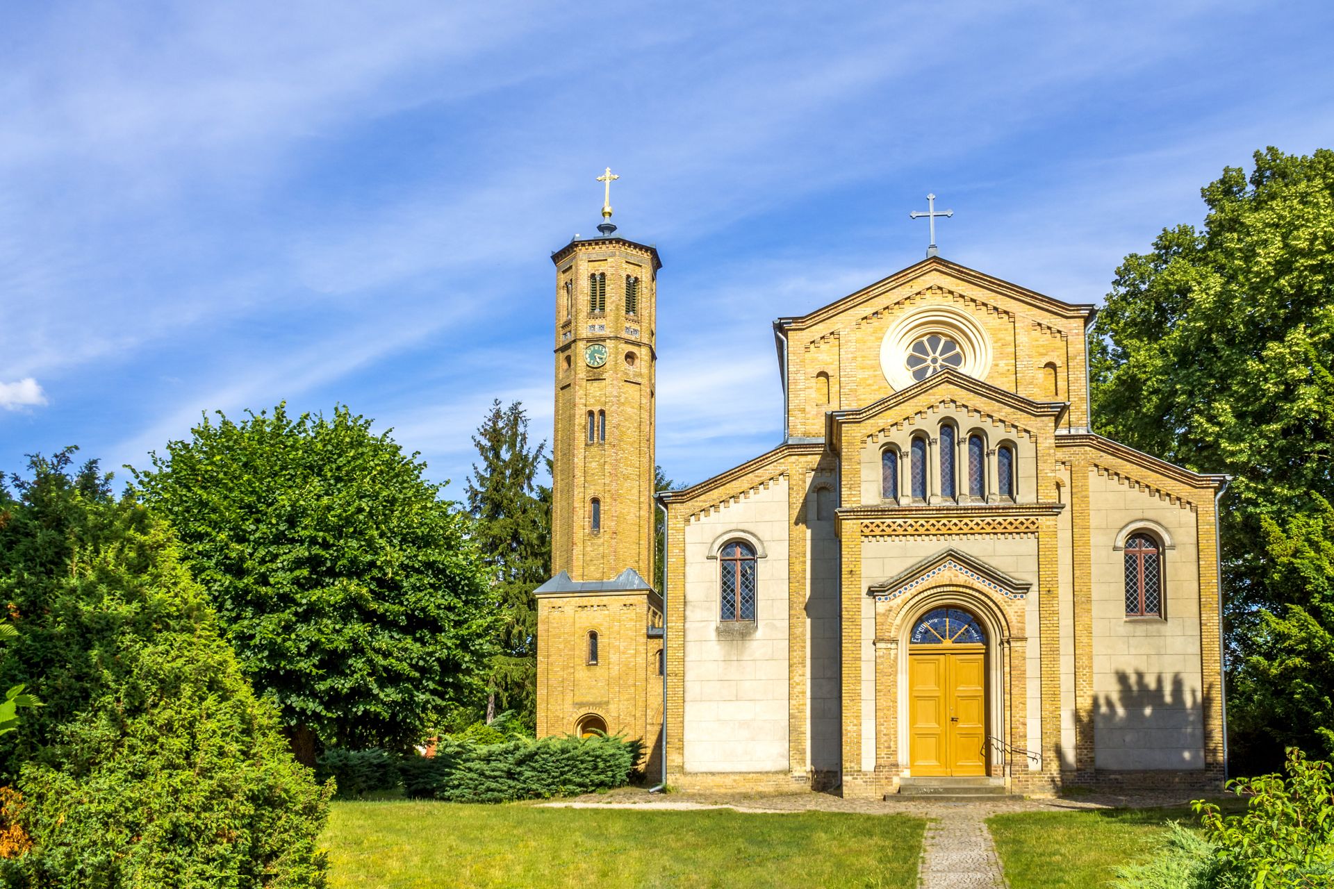 Eine Kirche mit einem Glockenturm inmitten eines von Bäumen umgebenen Feldes.