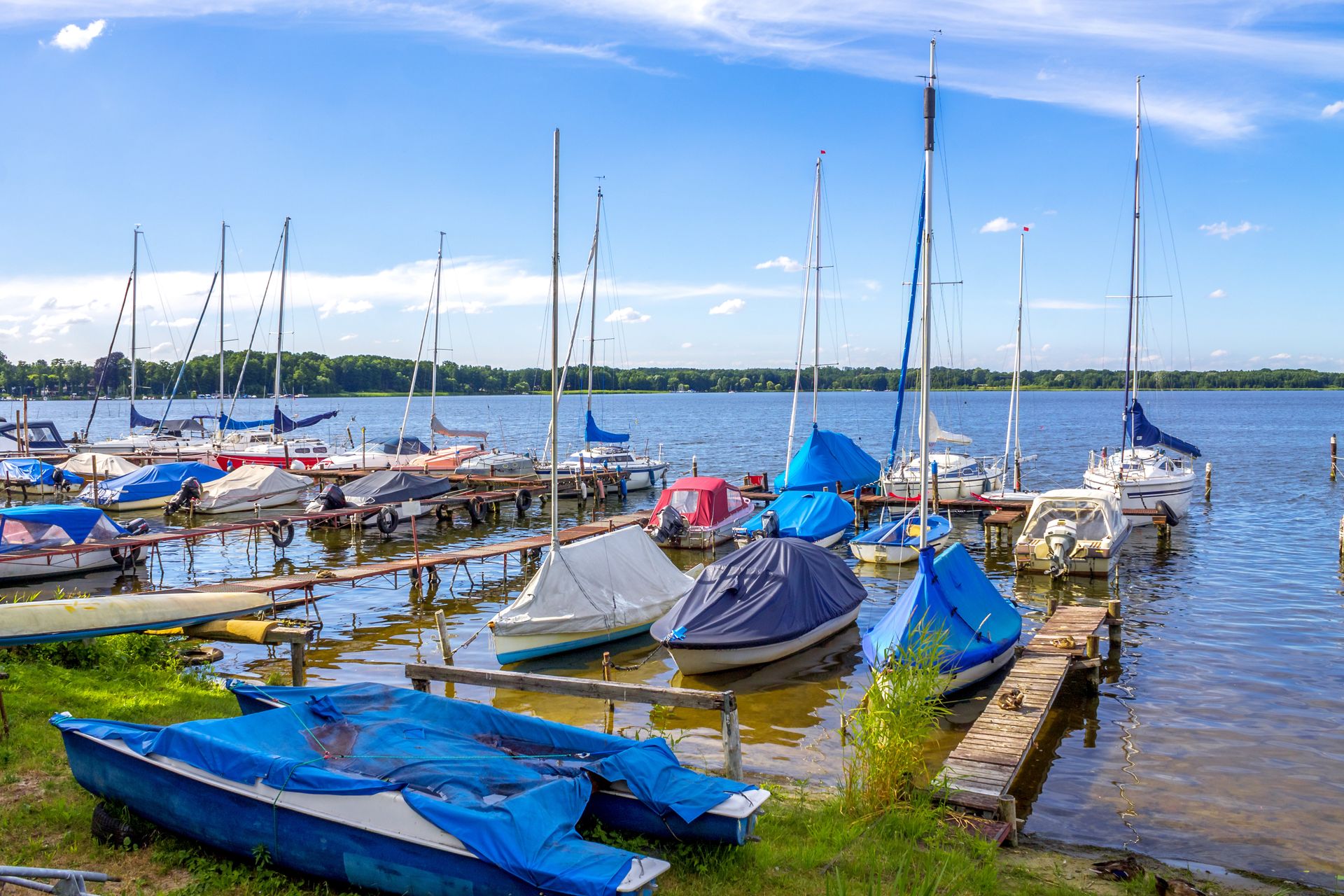 In einem Yachthafen an einem See liegen mehrere Boote vor Anker.
