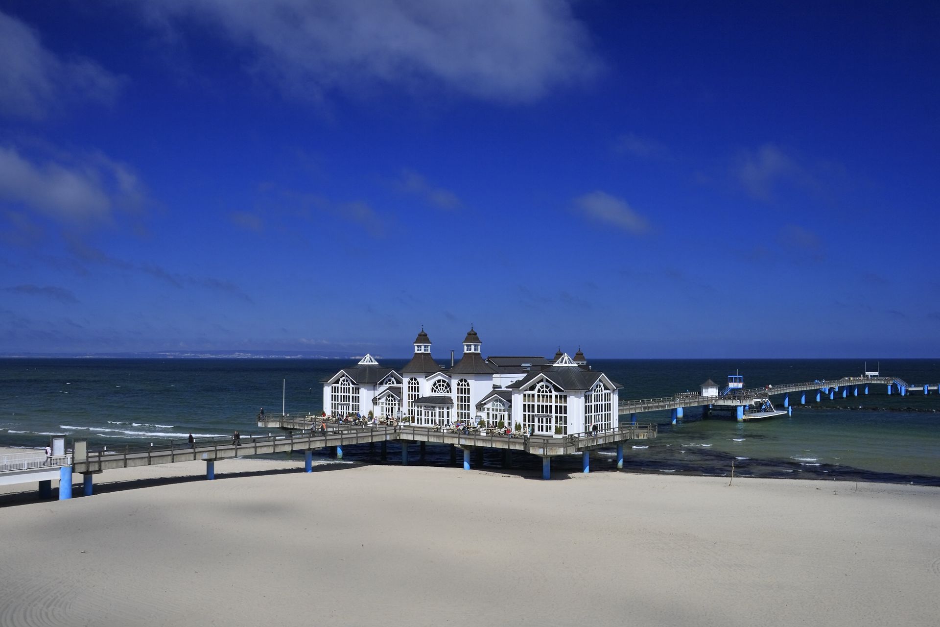 Ein Pier an einem Strand mit einem blauen Himmel im Hintergrund