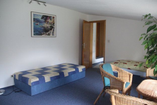 Ein Wohnzimmer mit einem Bett und Stühlen und einem Bild an der Wand