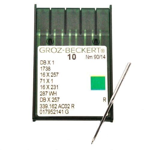 Groz-Beckert sewing machine needles in a white and green package, with one needle laid diagonally beside it