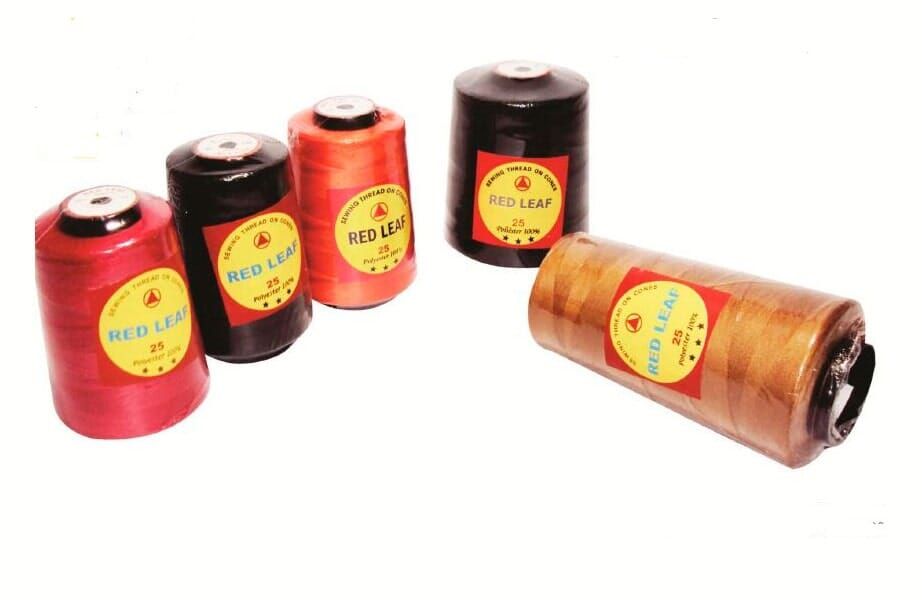 Five colorful spools of thread in red, black, orange, brown and tan on a white background