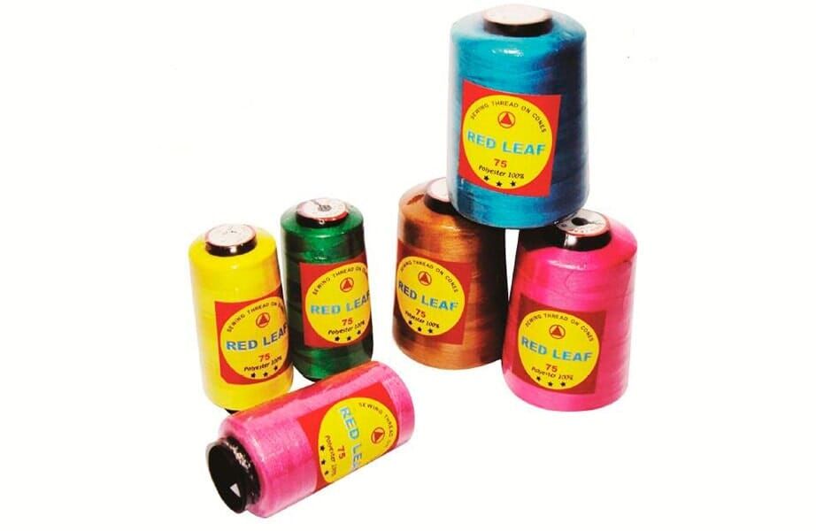 Colorful thread spools in pink, blue, green, brown, and red, arranged on a white background