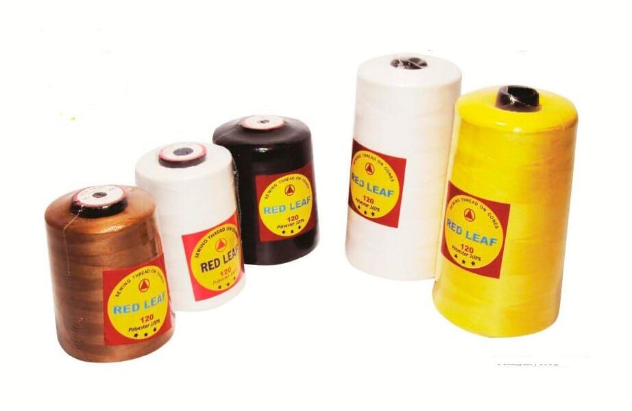 Five large thread spools in brown, white, black, and yellow on a white background