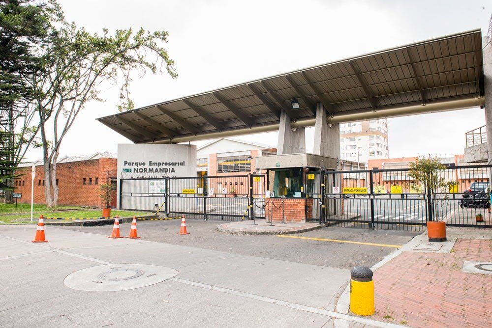 Closed gate at a covered entrance with orange cones and a sign on a brick-and-metal facility entrance