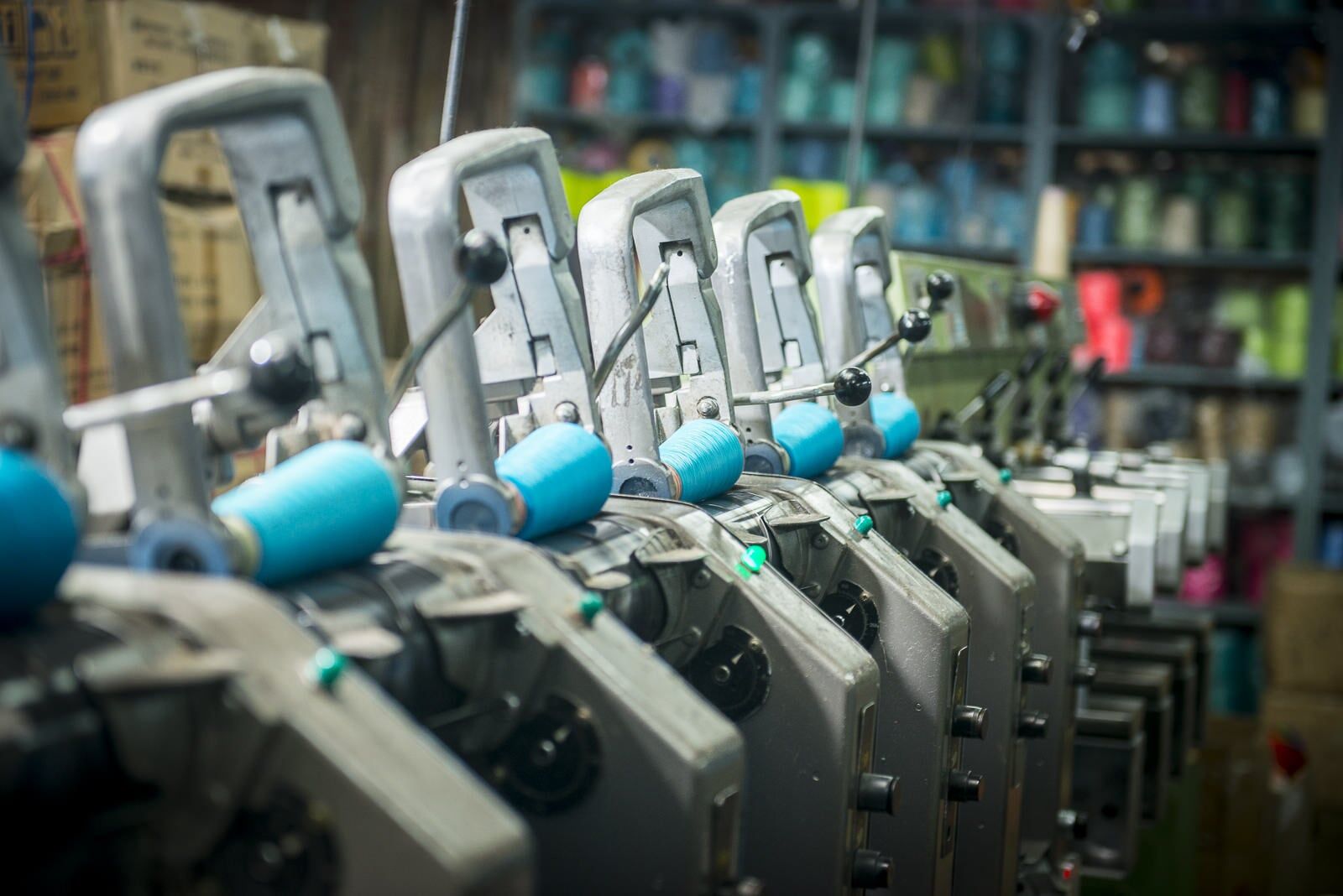 Row of industrial metal machines with blue rollers in a factory workshop