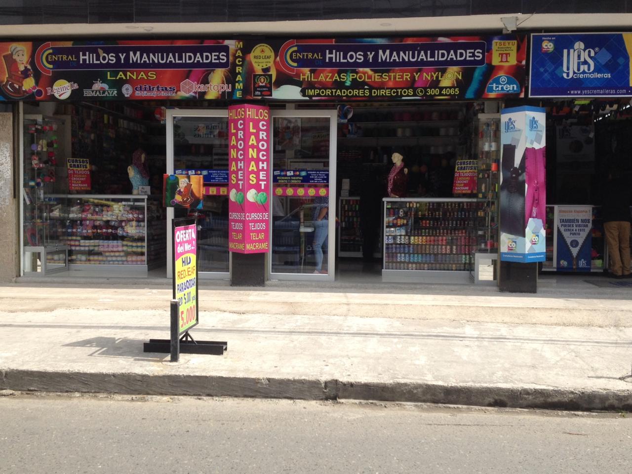 Storefront of a colorful handmade crafts shop with signs, displays, and a sidewalk entrance