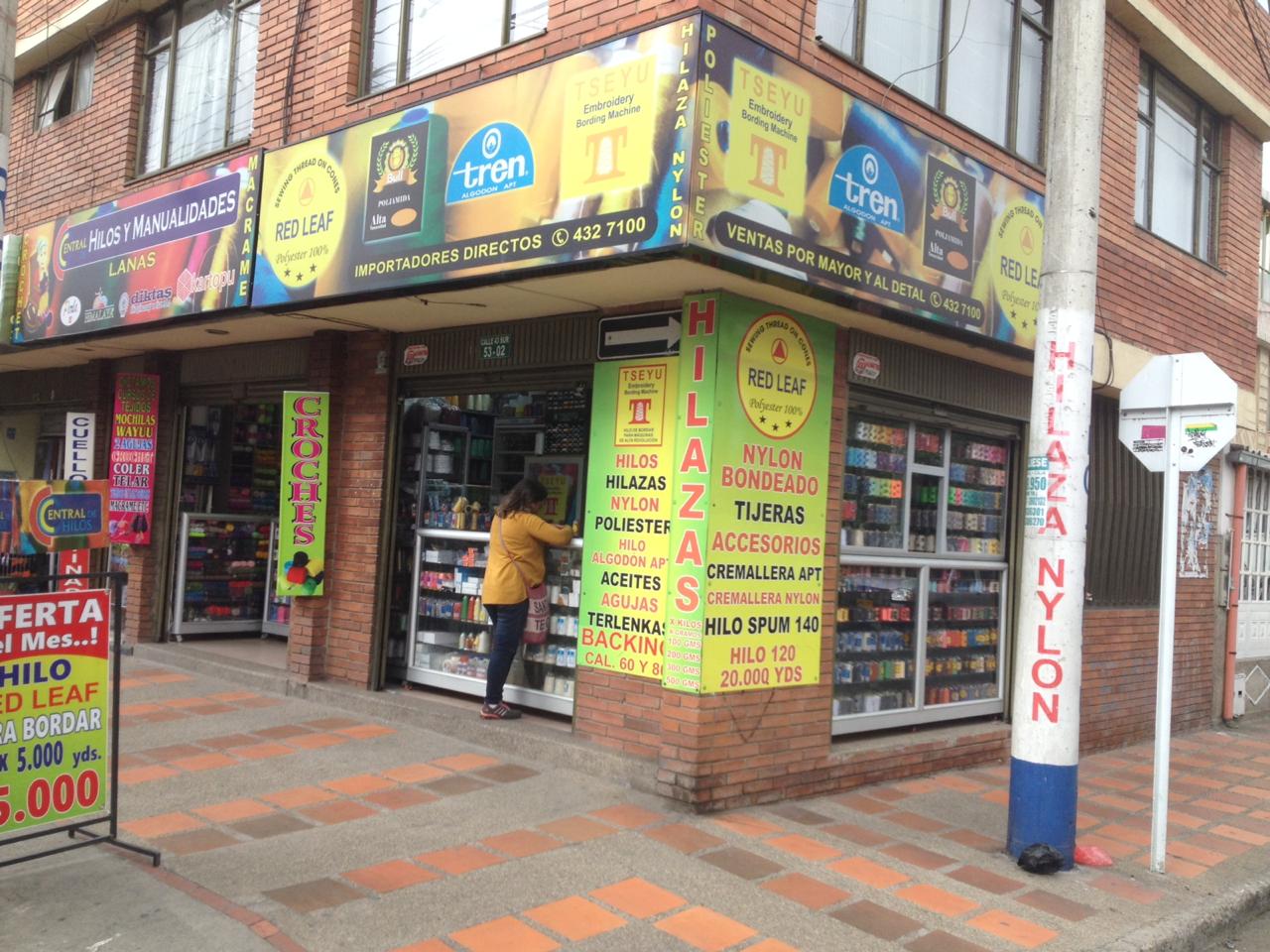Corner storefront with colorful Spanish signs and a person in a yellow shirt at the entrance