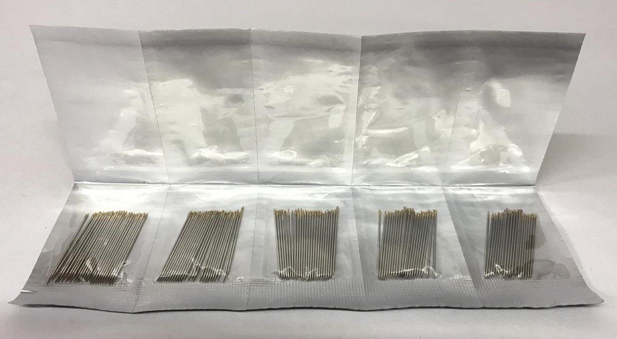 Five small clear plastic bags holding assorted metal screws and fasteners on a white surface