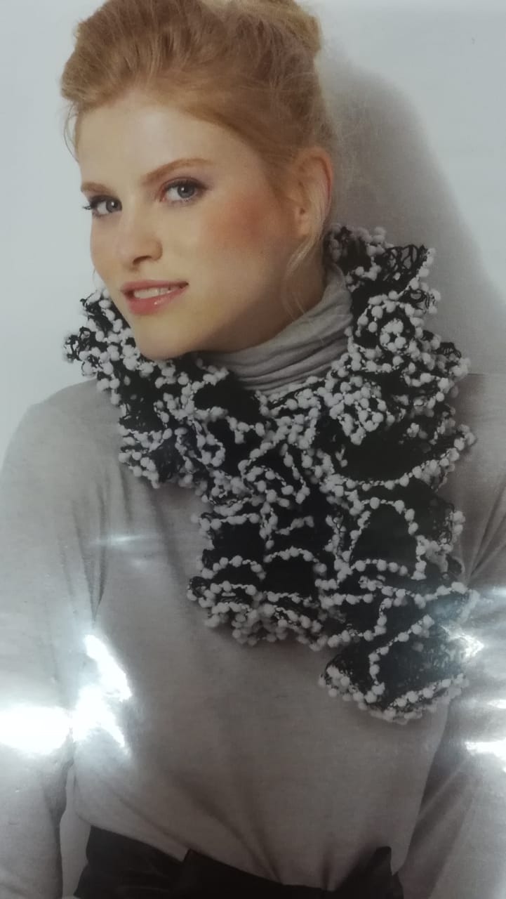 Portrait of a person in a gray top with a black-and-white patterned scarf against a light background