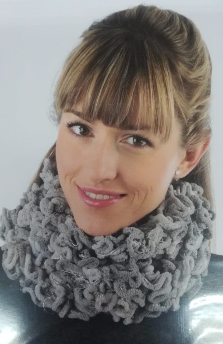 Smiling woman wearing a gray knit scarf against a light background