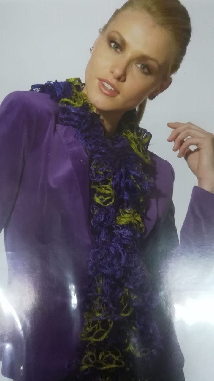 Fashion model in a purple satin blouse with a ruffled black-and-purple scarf, posing against a light background