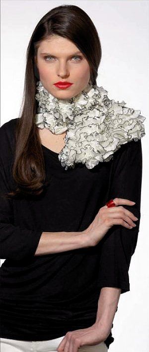 Fashion model in a black dress with a large white floral collar, posing against a plain white background