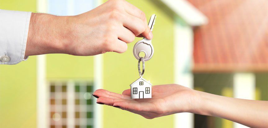 A person is handing a house key to another person.