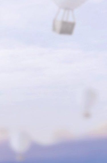 Verschwommene Sicht auf weiße Heißluftballons, die in einem hellblauen Himmel schweben.