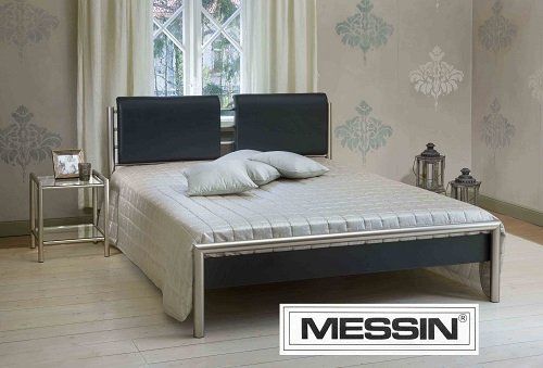 Moderner Bettrahmen mit gepolstertem Kopfteil und Bettzeug in einem Schlafzimmer mit gemusterter Tapete und Beistelltisch.
