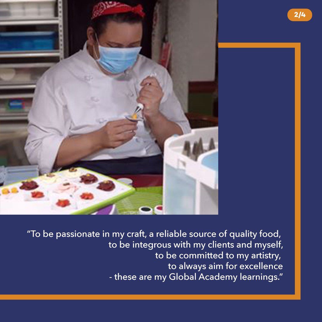 Chef in white uniform and mask piping decorations onto a dessert at a kitchen worktable