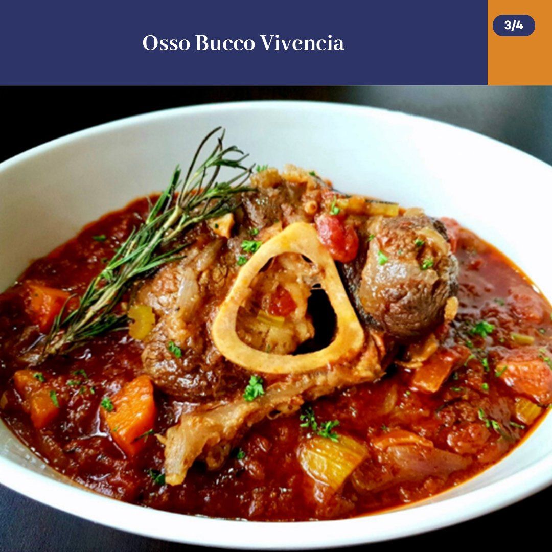 Bowl of osso buco in rich red sauce, garnished with herbs and vegetables, on a white plate