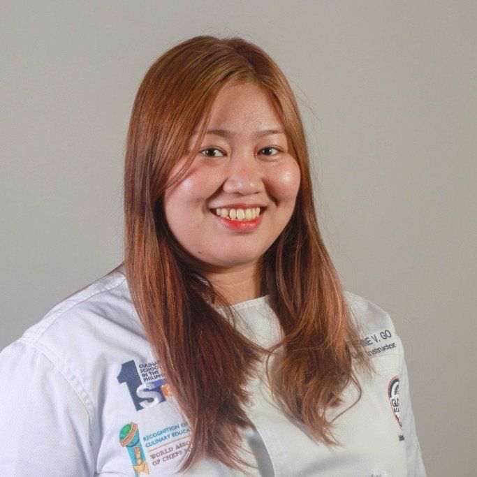 Smiling person in a white shirt against a plain gray background