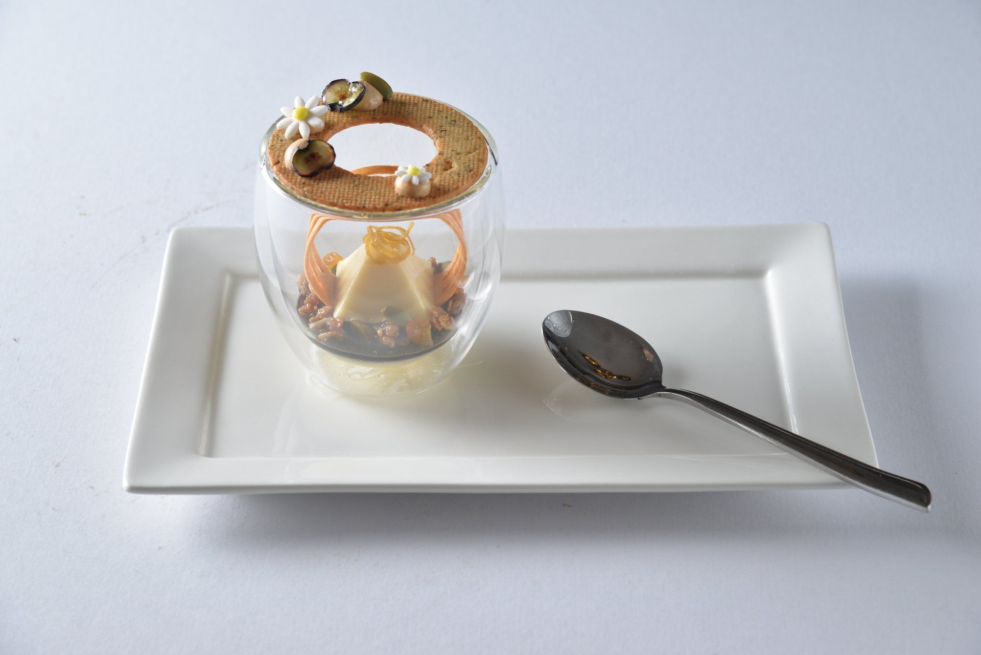 Dessert in a glass dish on a white tray with a spoon beside it