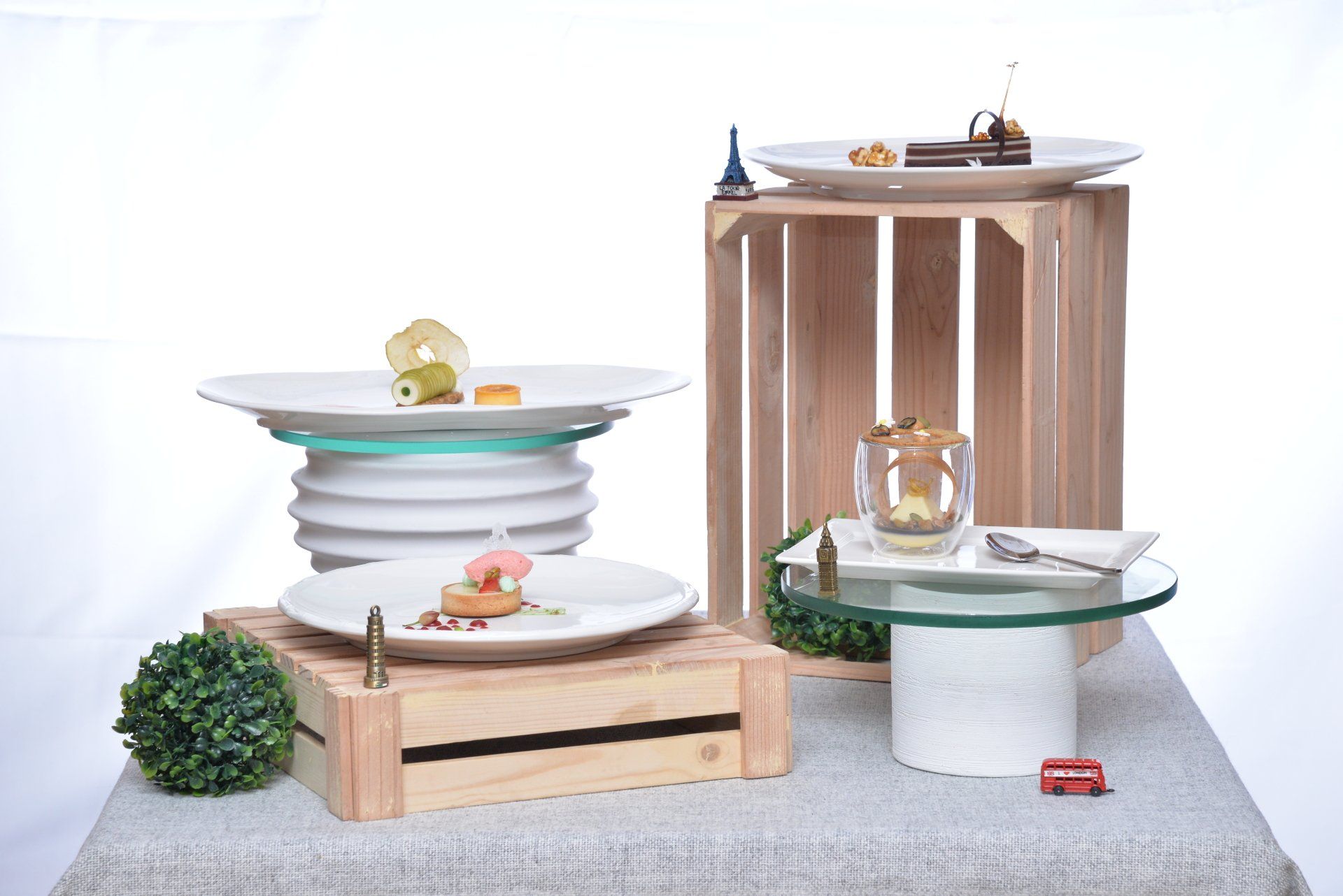 Modern pet furniture with stacked bowls, wooden stands, and small figurines on a gray surface