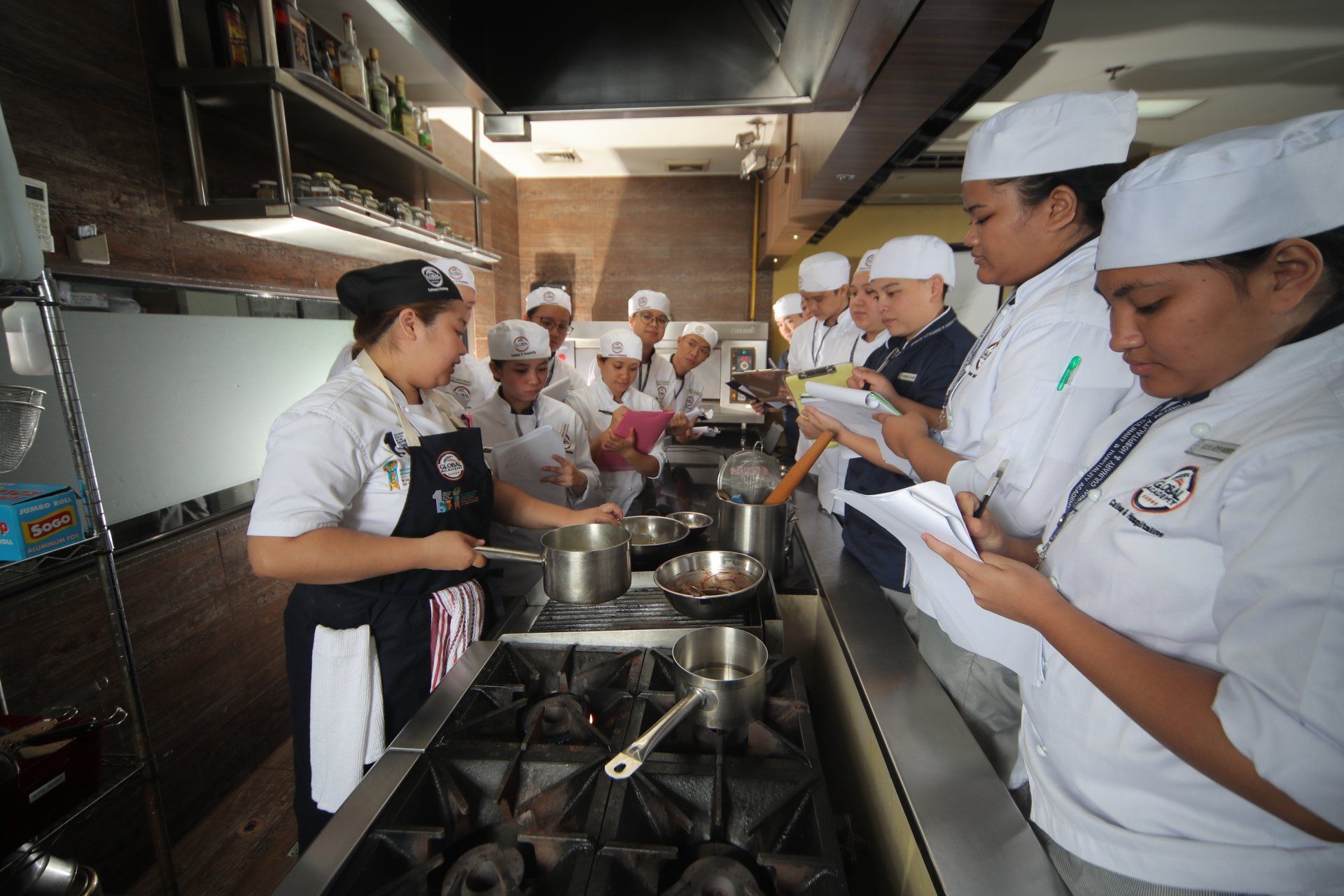 Chefs in white uniforms and hats cooking together in a busy commercial kitchen