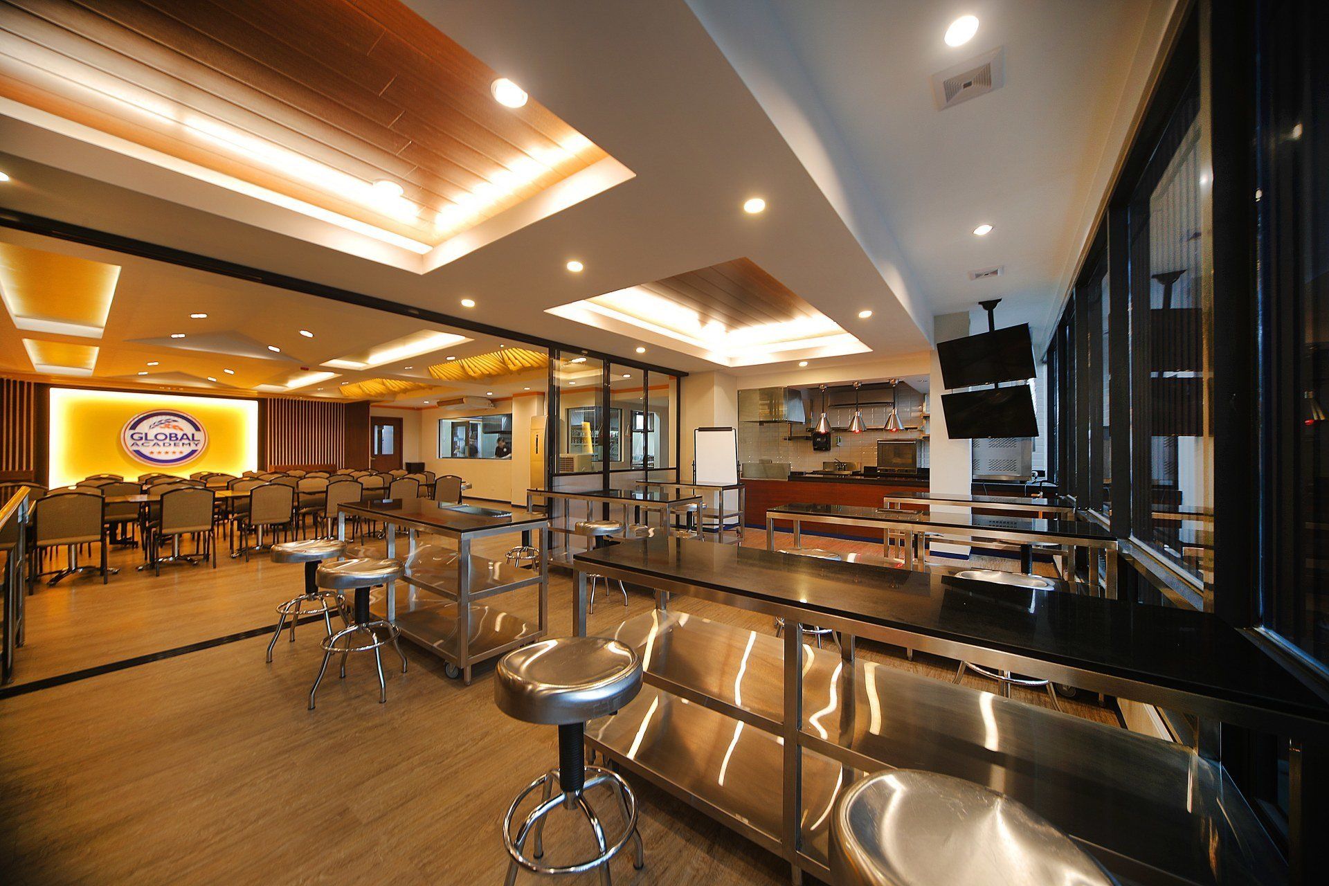Modern bar and lounge interior with warm lighting, stools, tables, and a reflective counter.