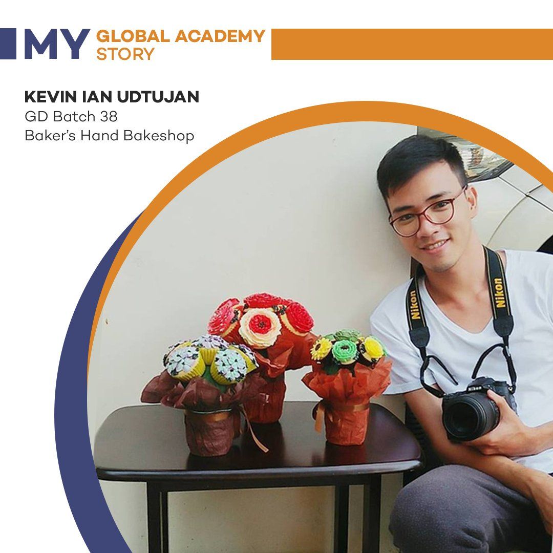 Young man with camera beside colorful floral arrangement on a table, framed by an orange-and-blue circular border