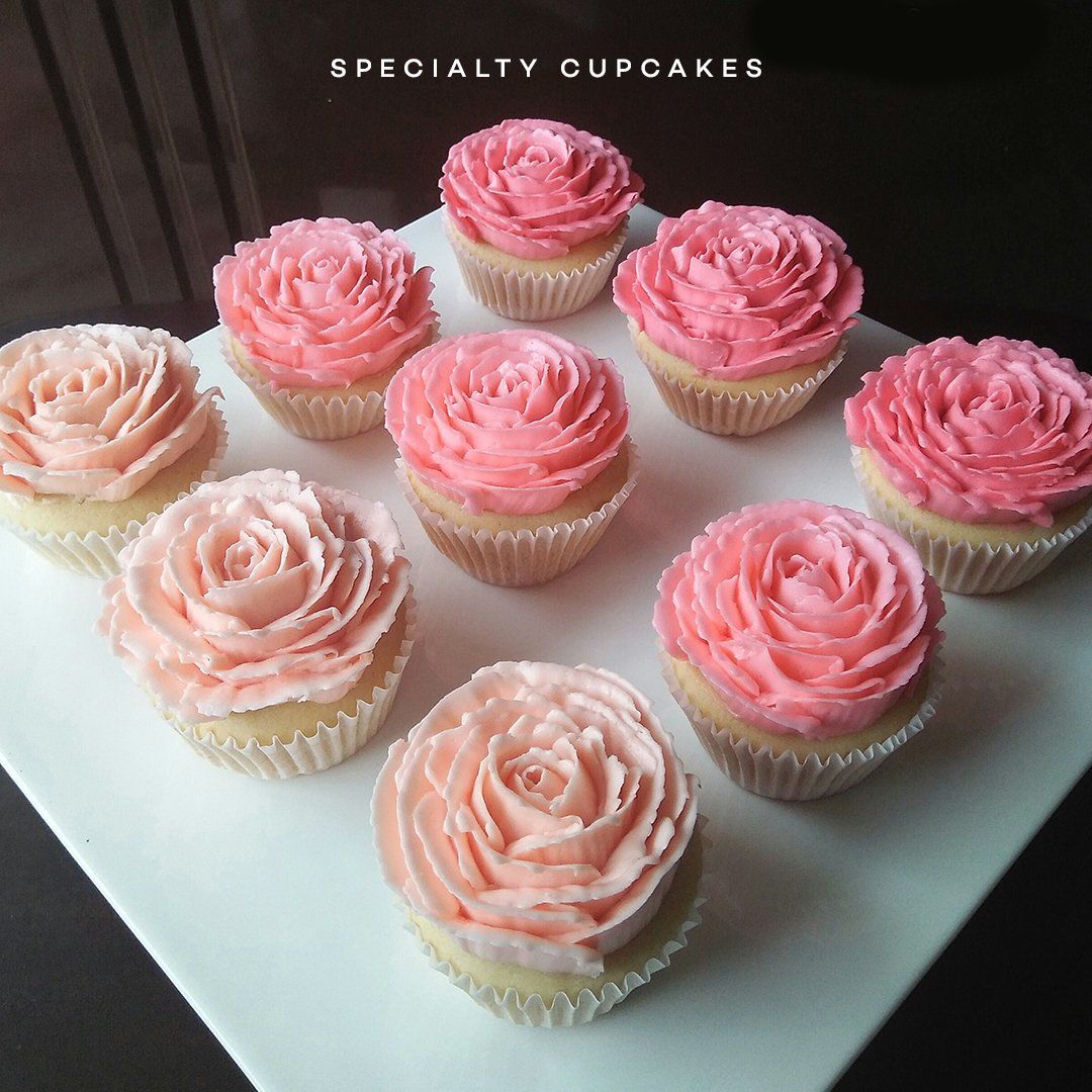 Assorted pink frosted cupcakes arranged on a white platter