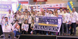 Group celebrating on stage with a large “CHAMPION” banner and balloons at a back-to-school event.