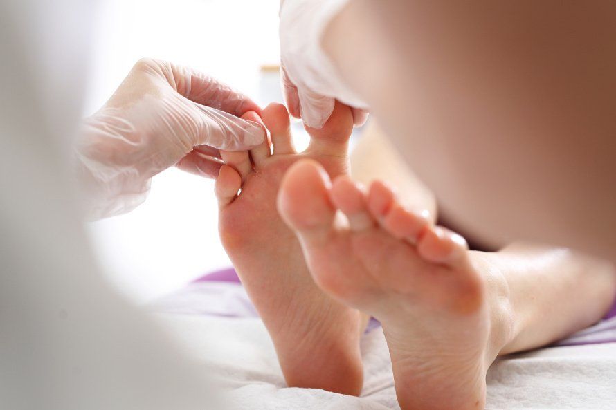 Uma mulher está tendo os pés examinados por um médico.