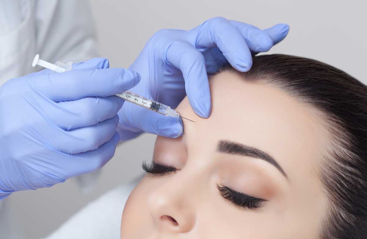 Uma mulher está recebendo uma injeção de botox na testa.