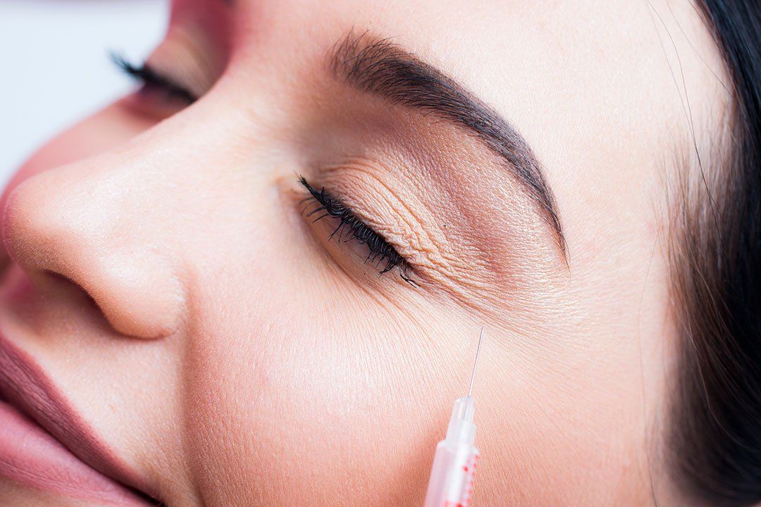 Uma mulher está recebendo uma injeção de botox na bochecha.
