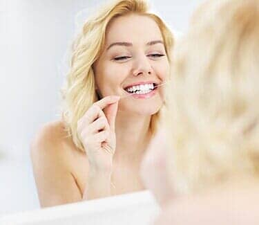 Woman using dental floss — Dental Office in Virginia Beach, VA Woman using dental floss — Dental Office in Virginia Beach, VA