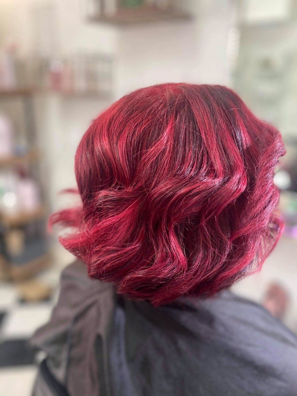A woman with red hair is sitting in a chair in a salon.