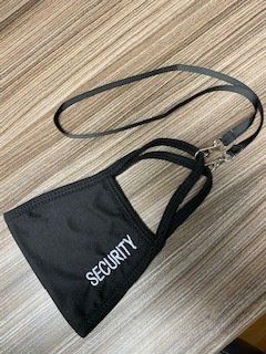 Black security lanyard and badge holder on a wooden floor.