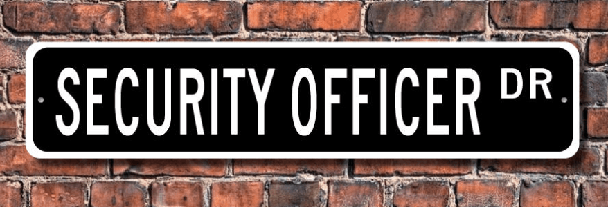 Black street sign reading “SECURITY OFFICER DR.” on a brick wall