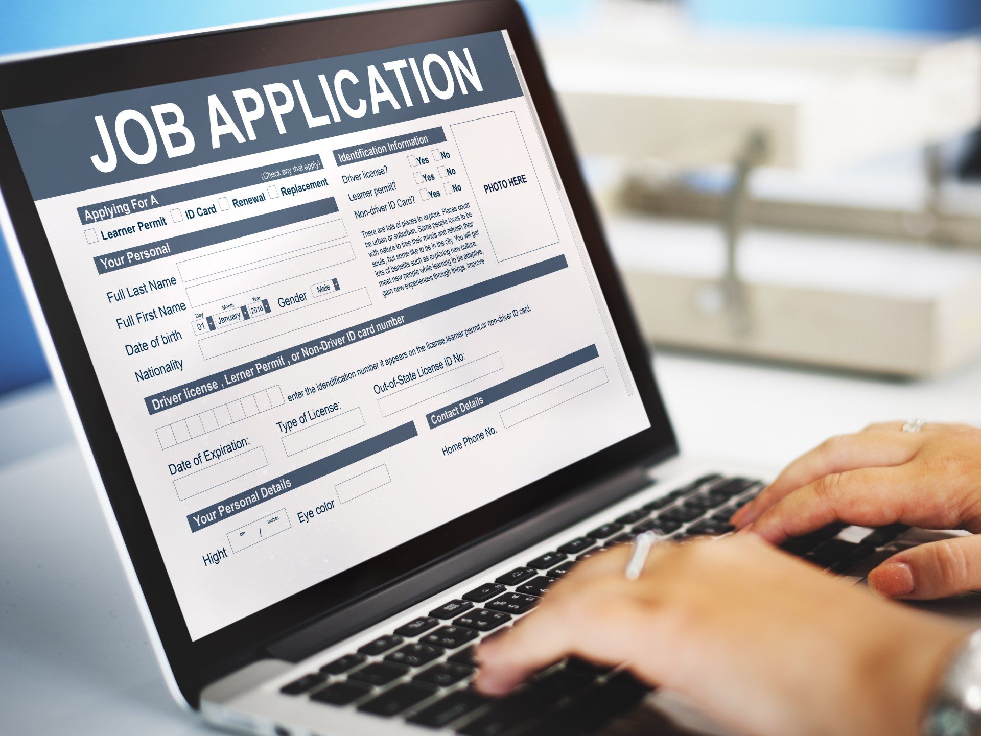 Hands typing on a laptop showing a job application form on screen