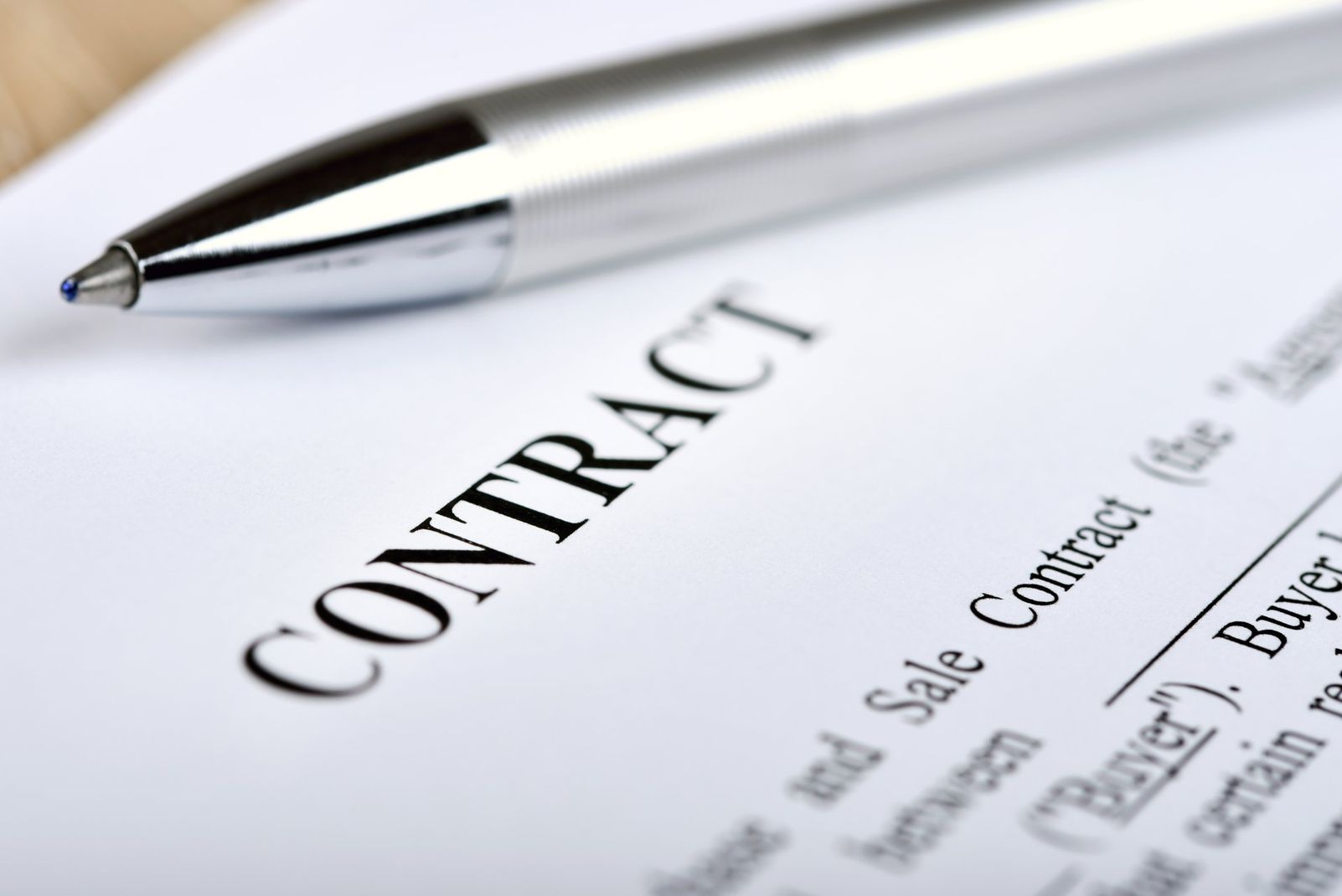 Pen above a contract document with the word “CONTRACT” visible