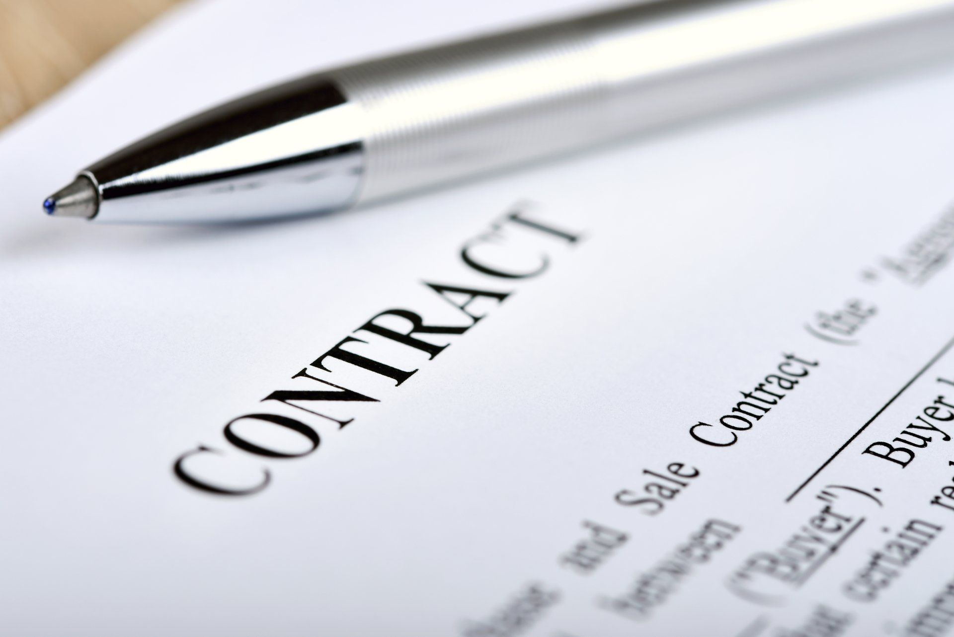 Pen above a contract document with the word “CONTRACT” visible