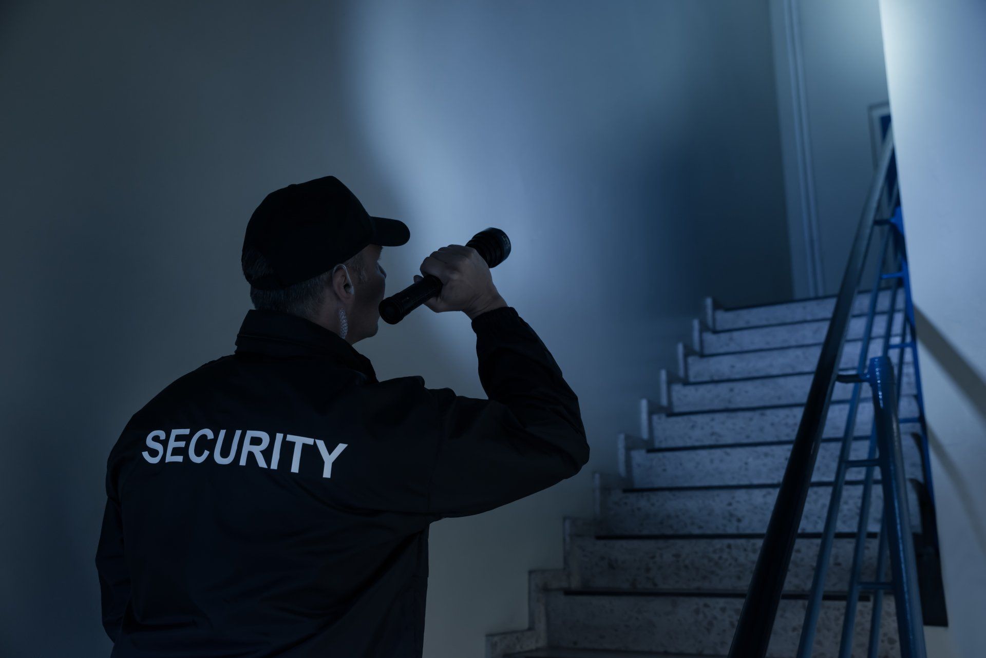 Security guard using binoculars in a dim stairwell