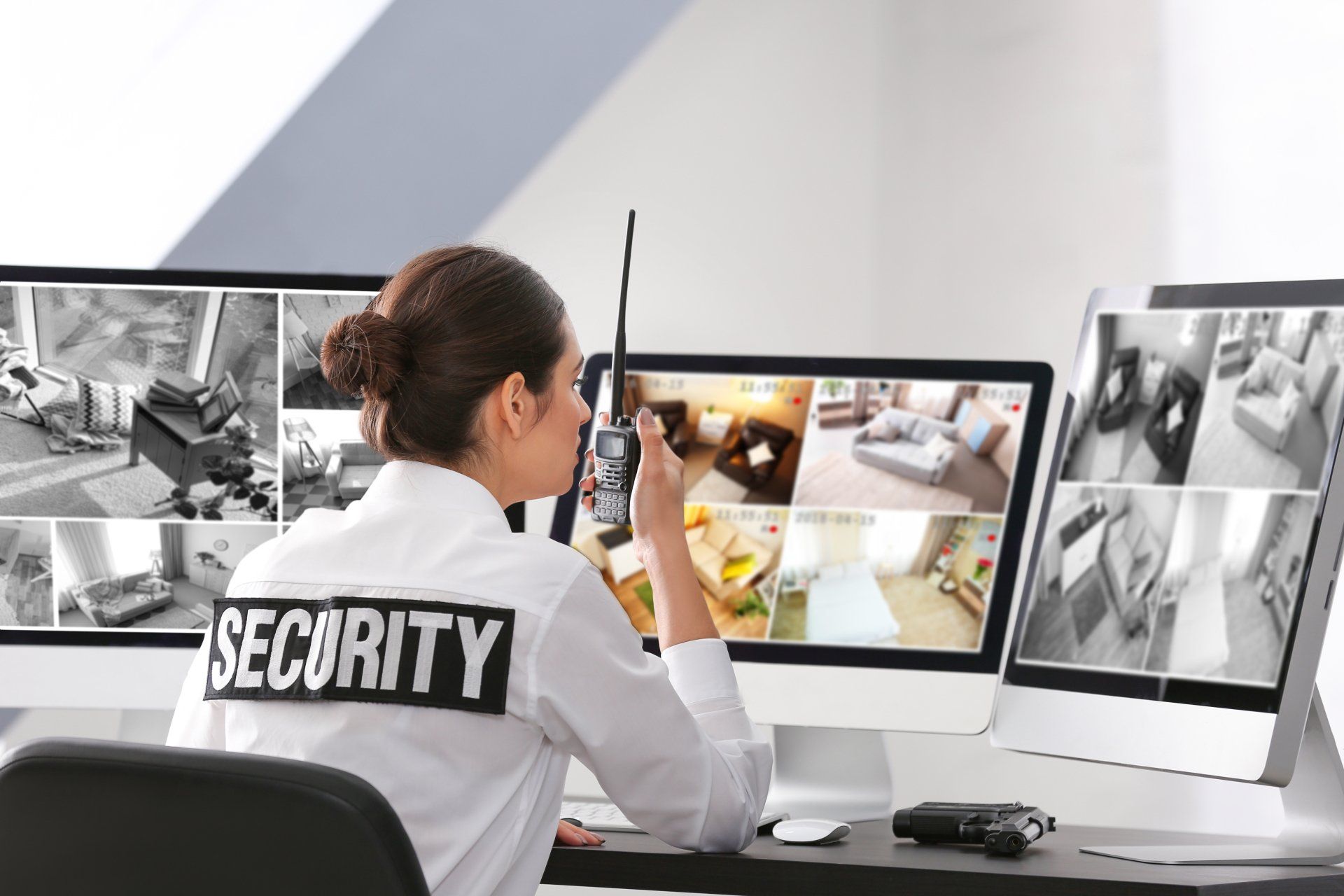 Security guard monitoring surveillance cameras at a desk with multiple screens