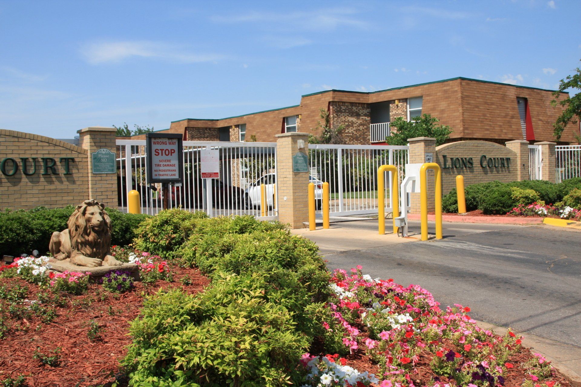 Gated Community main entrance with a lion statue with Lions Court Apartments sign