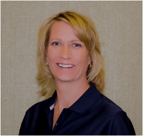 A woman in a blue shirt is smiling for the camera