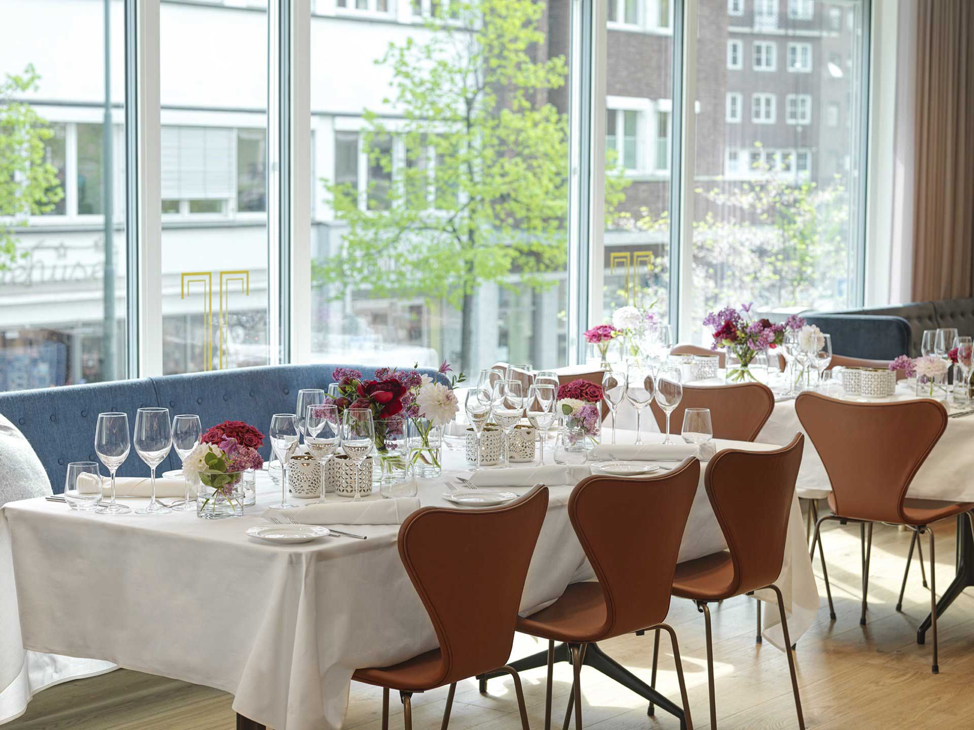 Bord i restauranten dekket med servise og blomsterbuketter