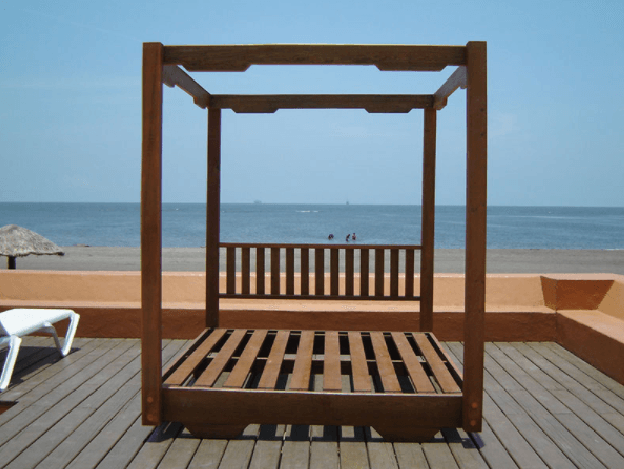 Tumbona de madera en una terraza de playa frente al océano.
