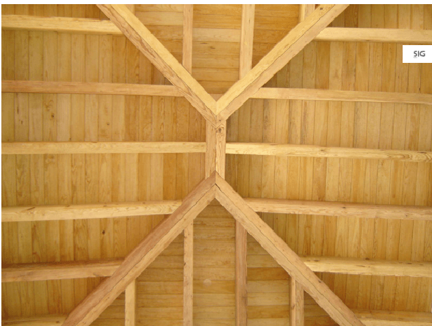 Techo de madera con vigas y cabrios a la vista que forman un patrón simétrico.
