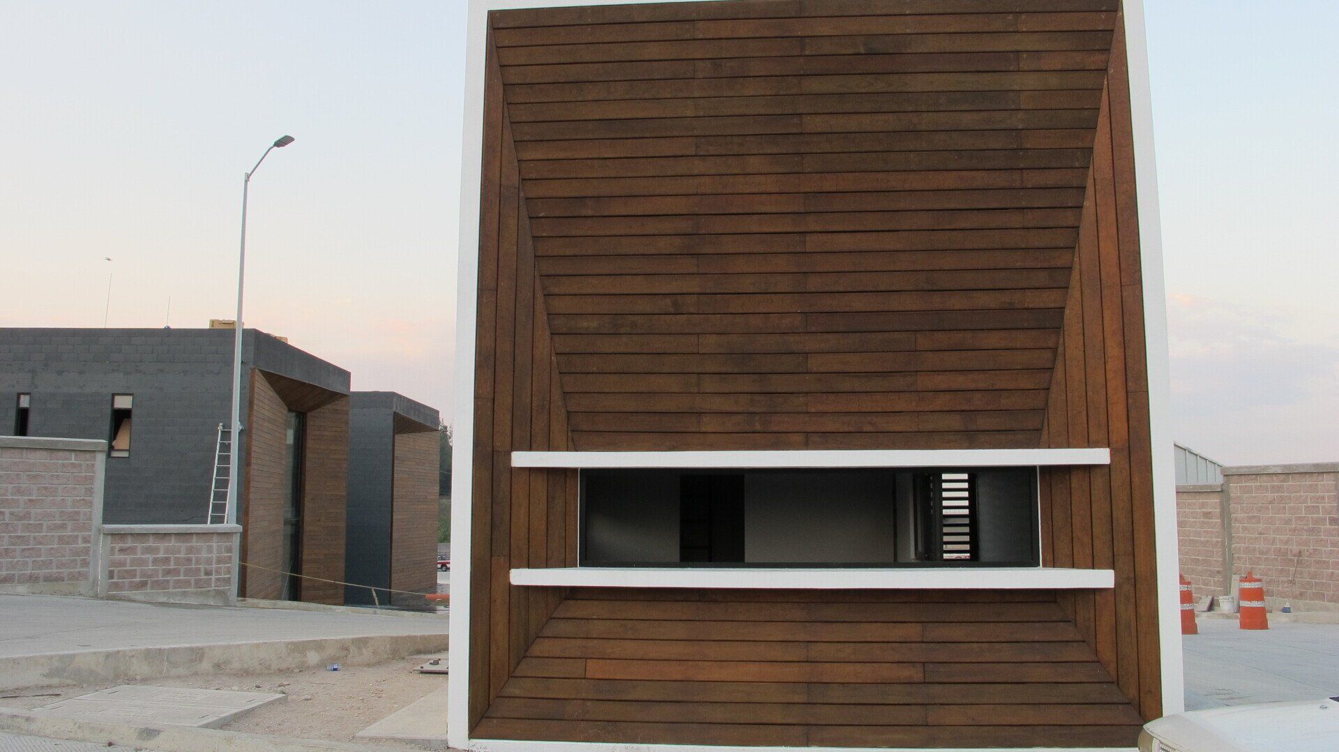 Fachada moderna de madera con una pequeña ventana horizontal y molduras blancas en el exterior.