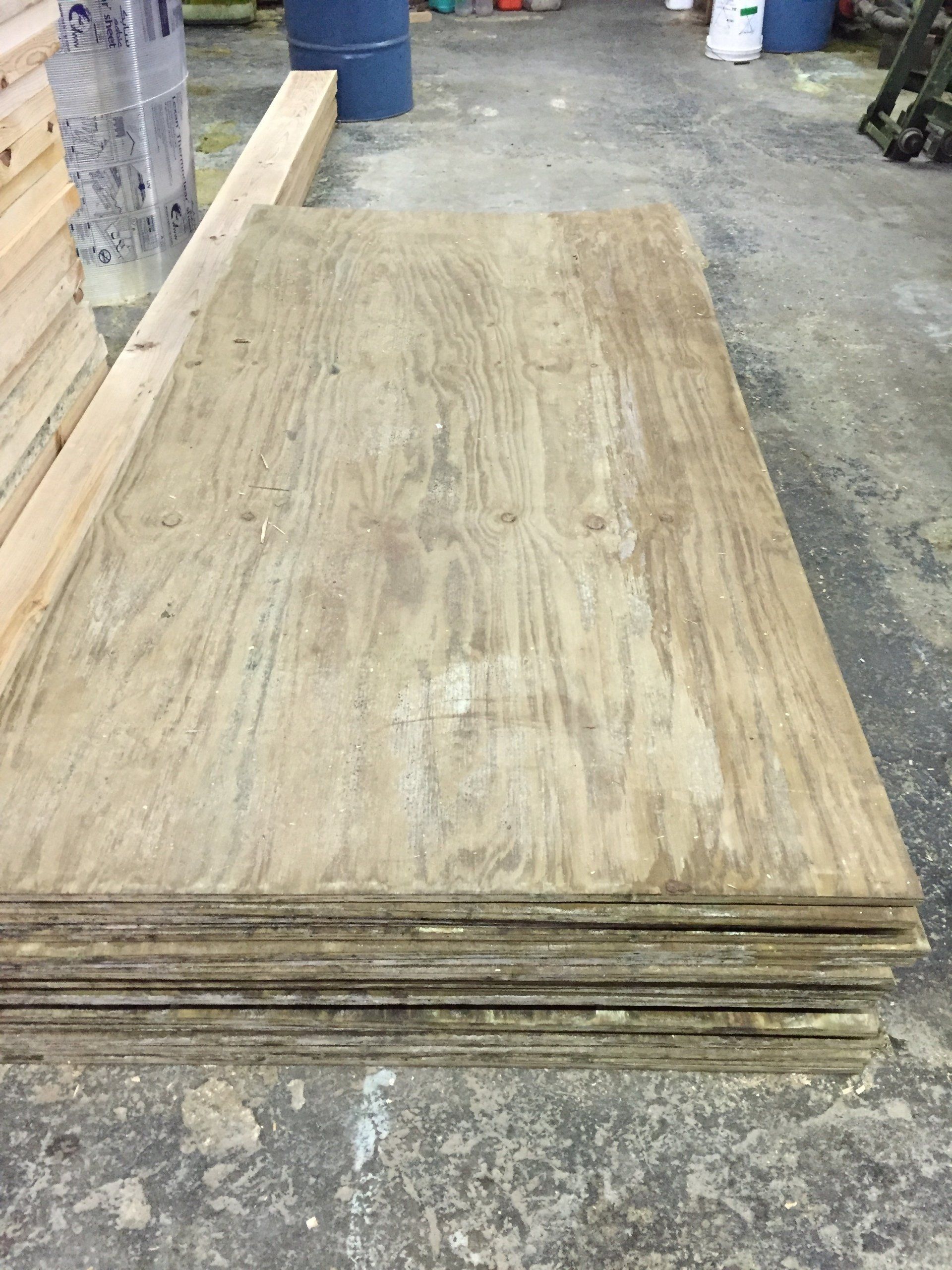 Pila de láminas de madera contrachapada en un taller, con una tabla larga apoyada encima.